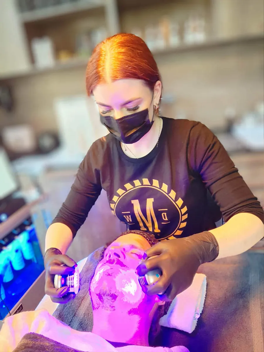 Kosmetikerin bei einer Gesichtsbehandlung mit LED-Licht für Männer