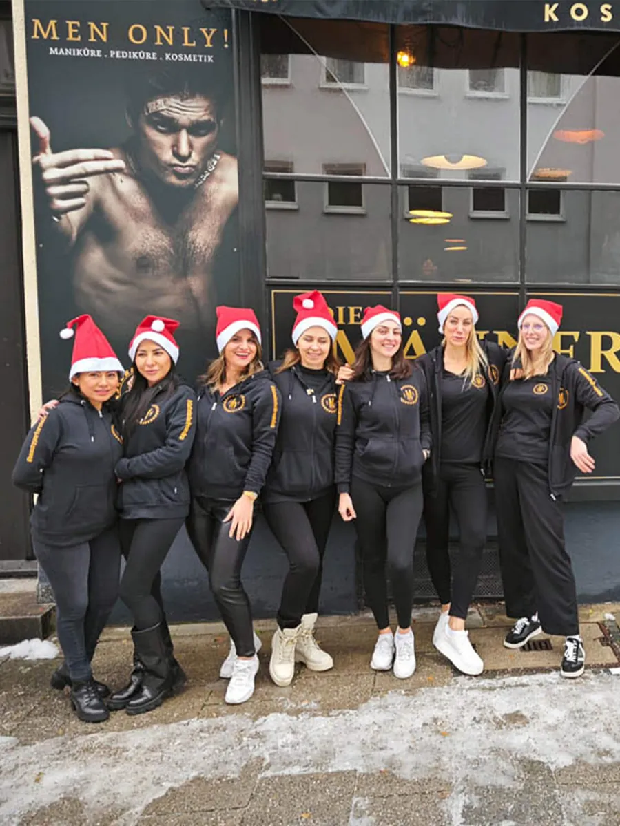 Team der Männer Werkstatt mit Weihnachtsmützen vor dem Studio
