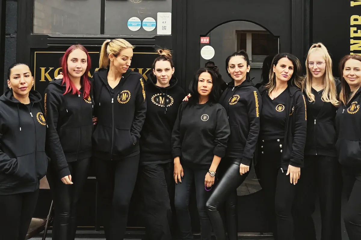 Das Team der Männer Werkstatt in schwarzer Kleidung vor dem Studio in München